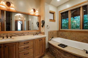 Bathroom with decorative backsplash, a bath, double vanity, and tile patterned flooring
