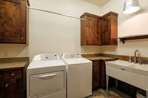 Laundry area with washer and clothes dryer, dark stone finish flooring, and cabinet space
