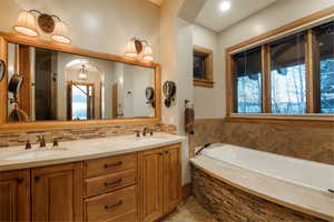 Bathroom with double vanity, a garden tub, a chandelier, and a shower with door