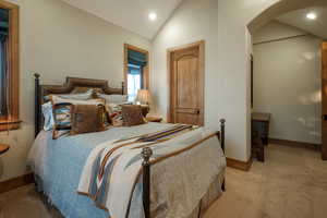 Bedroom featuring vaulted ceiling, recessed lighting, arched walkways, and light colored carpet