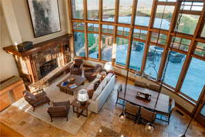 Living room featuring stone tile floors, a water view, a stone fireplace, and plenty of natural light