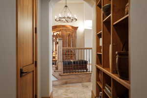 Wine area featuring a chandelier, stone tile flooring, and arched walkways