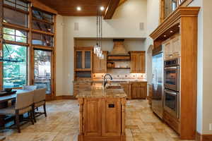 Kitchen with a high ceiling, stainless steel appliances, stone tile flooring, open shelves, and wood ceiling