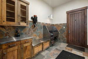 Interior space featuring tile walls, stone tile floors, pet washing station, and a wainscoted wall