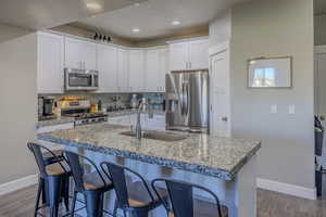 Kitchen with a breakfast bar, tasteful backsplash, appliances with stainless steel finishes, and a sink