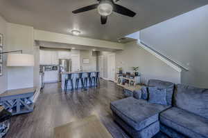 Living room with ceiling fan, dark wood-type flooring, visible vents, and a textured ceiling