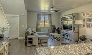 Living room featuring baseboards, wood finished floors, and a ceiling fan