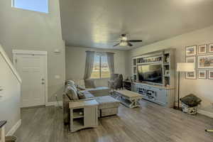 Living area with baseboards, a textured ceiling, wood finished floors, and a ceiling fan