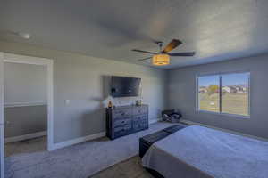 Bedroom featuring carpet flooring, ceiling fan, a textured ceiling, and baseboards