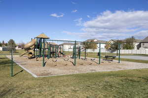 Community play area with a residential view, a lawn, and fence