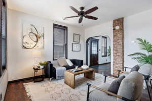 Living area with visible vents, baseboards, wood finished floors, arched walkways, and a ceiling fan