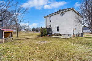 View of side of home featuring cooling unit, an outbuilding, a yard, and entry steps