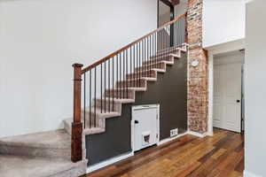Stairs featuring visible vents, baseboards, a high ceiling, and wood finished floors
