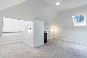 Additional living space with lofted ceiling with skylight, carpet flooring, and baseboards