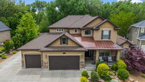 Craftsman-style home with stucco siding, a porch, stone siding, a shingled roof, and a garage