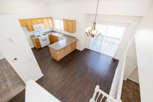 Kitchen featuring light brown cabinetry, a sink, plenty of natural light, white appliances, and a peninsula