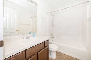 Bathroom featuring tile patterned floors, washtub / shower combination, toilet, and vanity