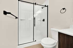 Bathroom with vanity, a shower stall, and toilet