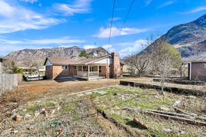 Back of property featuring a mountain view, brick siding, a chimney, and fence