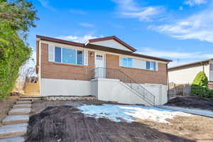 View of front of house featuring brick siding, an attached garage, and fence