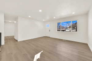 Interior space with wood finished floors, visible vents, baseboards, recessed lighting, and a textured ceiling