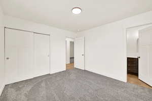 Unfurnished bedroom featuring light colored carpet, a closet, and baseboards