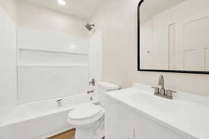 Bathroom with vanity, wood finished floors, recessed lighting, shower / washtub combination, and toilet