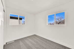 Carpeted spare room featuring visible vents and baseboards