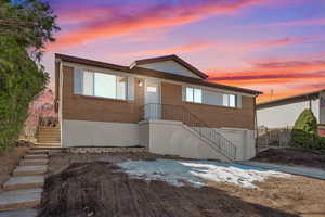 View of front of property with brick siding, stairs, and a garage