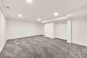 Finished basement featuring visible vents, recessed lighting, baseboards, and carpet