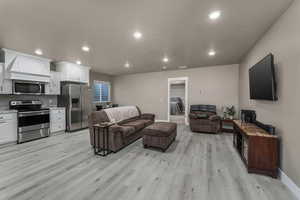 Living area with recessed lighting, baseboards, and light wood-style floors