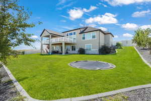 Back of house featuring a trampoline, stairway, a wooden deck, a fenced backyard, and stucco siding