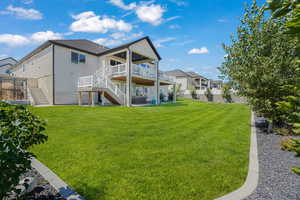Rear view of house featuring stairs, stone siding, a deck, and stucco siding