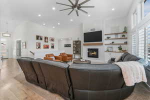 Living room featuring recessed lighting, a glass covered fireplace, a ceiling fan, and light wood finished floors