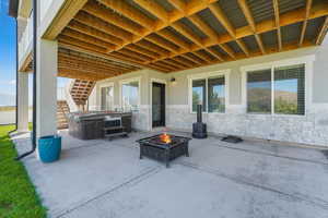 View of patio with an outdoor fire pit, stairway, and a hot tub