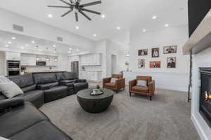 Living room with light carpet, visible vents, recessed lighting, and a glass covered fireplace