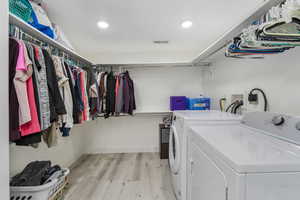 ADU Laundry room with visible vents, light wood-style flooring, washer and dryer, baseboards, and laundry area