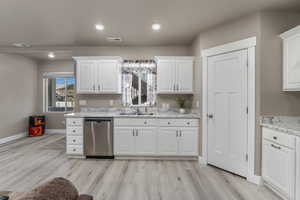 ADU Kitchen with a sink, visible vents, dishwasher, and white cabinets