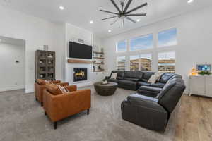Living area with a high ceiling, recessed lighting, baseboards, and a warm lit fireplace