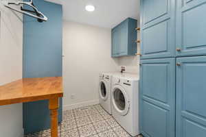 Washroom with light tile patterned floors, baseboards, cabinet space, and washer and clothes dryer