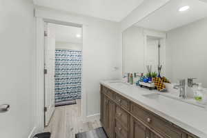 Bathroom featuring double vanity, wood finished floors, baseboards, and a sink