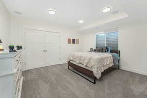 Bedroom featuring baseboards, a closet, and light carpet