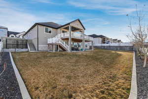 Rear view of property featuring stairway, a lawn, a fenced backyard, and a deck