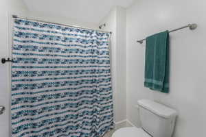 Full bath featuring curtained shower and toilet
