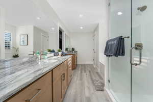 Bathroom featuring a shower stall, vanity, baseboards, and wood finished floors