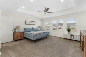 Bedroom featuring baseboards, recessed lighting, ceiling fan, light carpet, and a raised ceiling