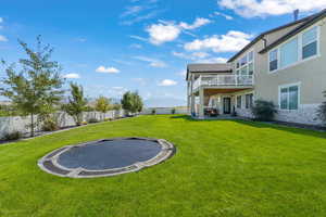 Fenced backyard with a trampoline, a deck, and a patio