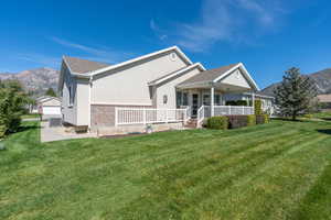 Back of property featuring a mountain view, covered porch, central AC, a lawn, and brick siding