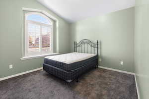 Bedroom featuring lofted ceiling, baseboards, and carpet floors