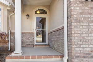 Doorway to property with stucco siding and brick siding